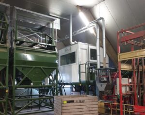 Indoor installation with metal extraction ducts above a potato sorting line, connected to a closed control cabin.