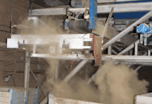 Stark staubige Kartoffelverarbeitungslinie, bei der der Staub an einem Aufprallpunkt auf dem Förderband freigesetzt wird.