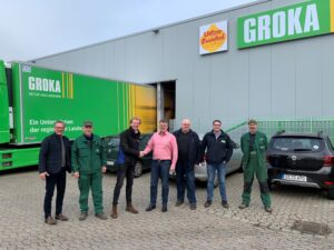 Photo de groupe des employés de Groka et de Jongejans devant le hall de traitement, avec un camion Groka en arrière-plan.