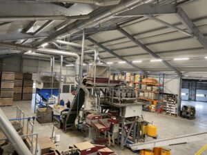 Überblick über die Kartoffelverarbeitungshalle mit den Extraktionslinien über der gesamten Anlage sowie verschiedenen Maschinen und Lagerregalen.