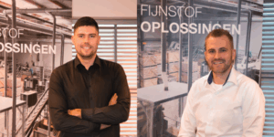 Two new representatives from Jongejans Luchttechniek pose in front of banners about particulate matter solutions.