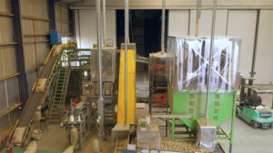 Übersicht über die komplette Verarbeitungslinie mit Förderbändern, Staubschutzzelten und Absaugrohren in der Kartoffelhalle.