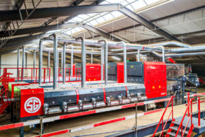 Bovenaanzicht van de optische sorteerlijn met afzuigbuizen en loopplatform.