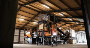 Large sorting line with bunkers and conveyor belts in an agricultural shed.