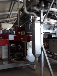 Nahaufnahme von Absaugkanälen und einer Staubabsauganlage, die in der Nähe der Verpackungsmaschine installiert ist.