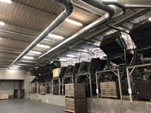 The Jongejans Luchttechniek extraction system above the sorting lines at AWEX, with long air ducts that remove dust and skins.