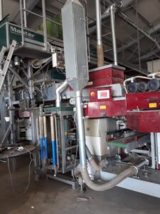 Staubabsauganlage und Rohrleitungen, die an eine rote Verpackungsmaschine angeschlossen sind.