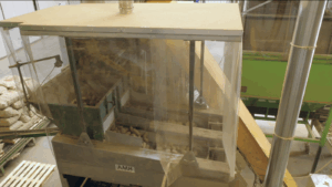 Verpackte Sortiermaschine mit einem transparenten Stoffzelt, in dem Kartoffeln geteilt und verarbeitet werden.